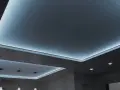 Nowoczesny sufit napinany z subtelnym, niebieskim podświetleniem tworzy relaksującą atmosferę.
