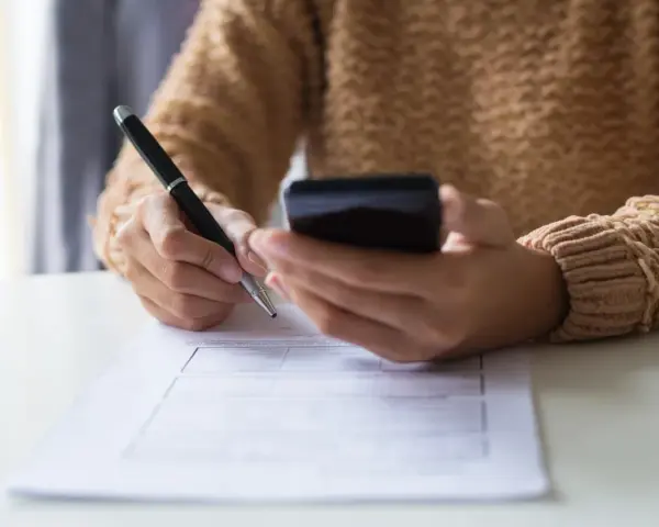 Kobieta z telefonem w dłoni wypełnia formularz, dokonując zgłoszenia darowizny online.
