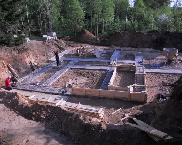 Budowa fundamentów domu. W wykopie widać zbrojenie i szalunki. Pracownicy przygotowują teren pod betonowanie. To będzie solidny chudziak!