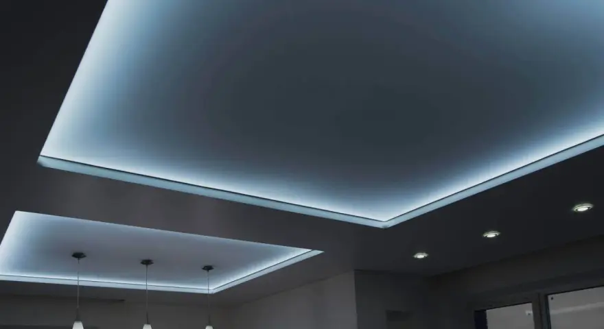 Nowoczesny sufit napinany z subtelnym, niebieskim podświetleniem tworzy relaksującą atmosferę.