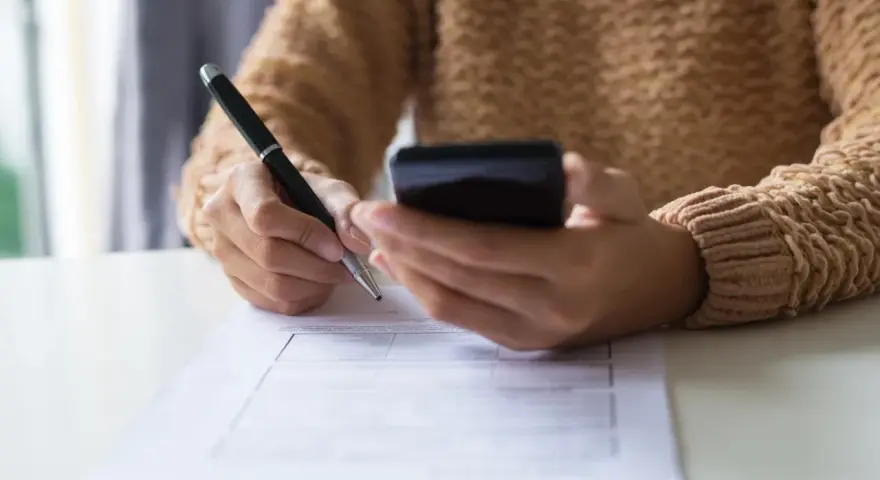 Kobieta z telefonem w dłoni wypełnia formularz, dokonując zgłoszenia darowizny online.